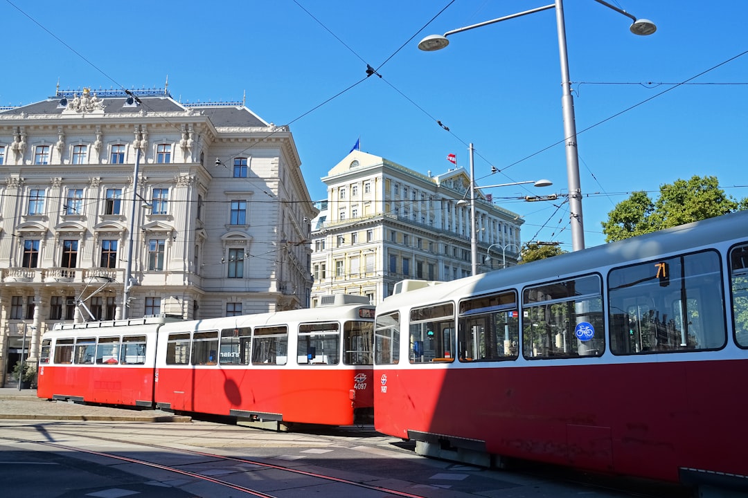 red and white tram on road near white concrete building during daytime