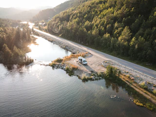 A comfortable hotel shuttle van parked by the riverside with lush greenery around.
