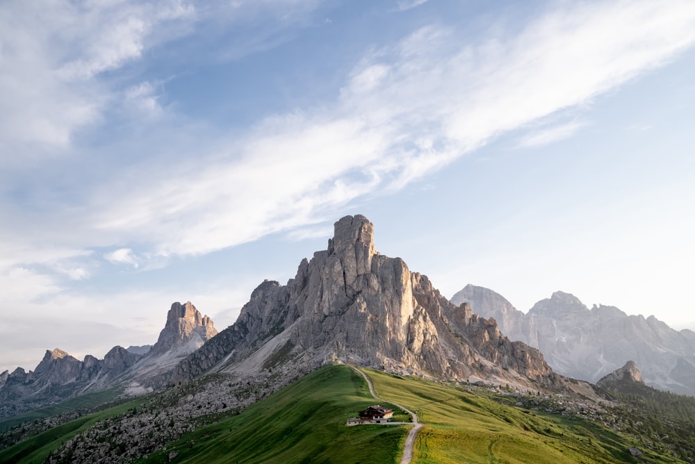 campo di erba verde vicino alla montagna rocciosa sotto nuvole bianche durante il giorno