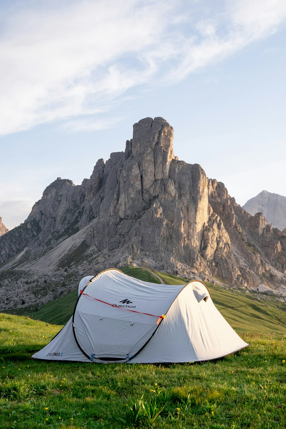 tenda bianca sul campo di erba verde vicino alla montagna rocciosa durante il giorno