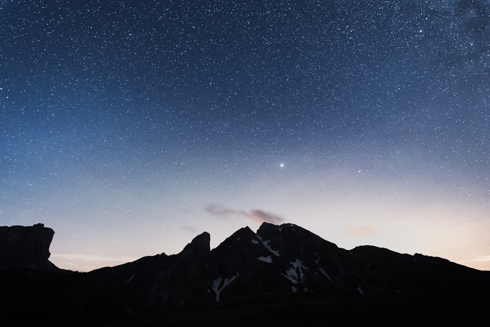 black and white mountains under blue sky during night time