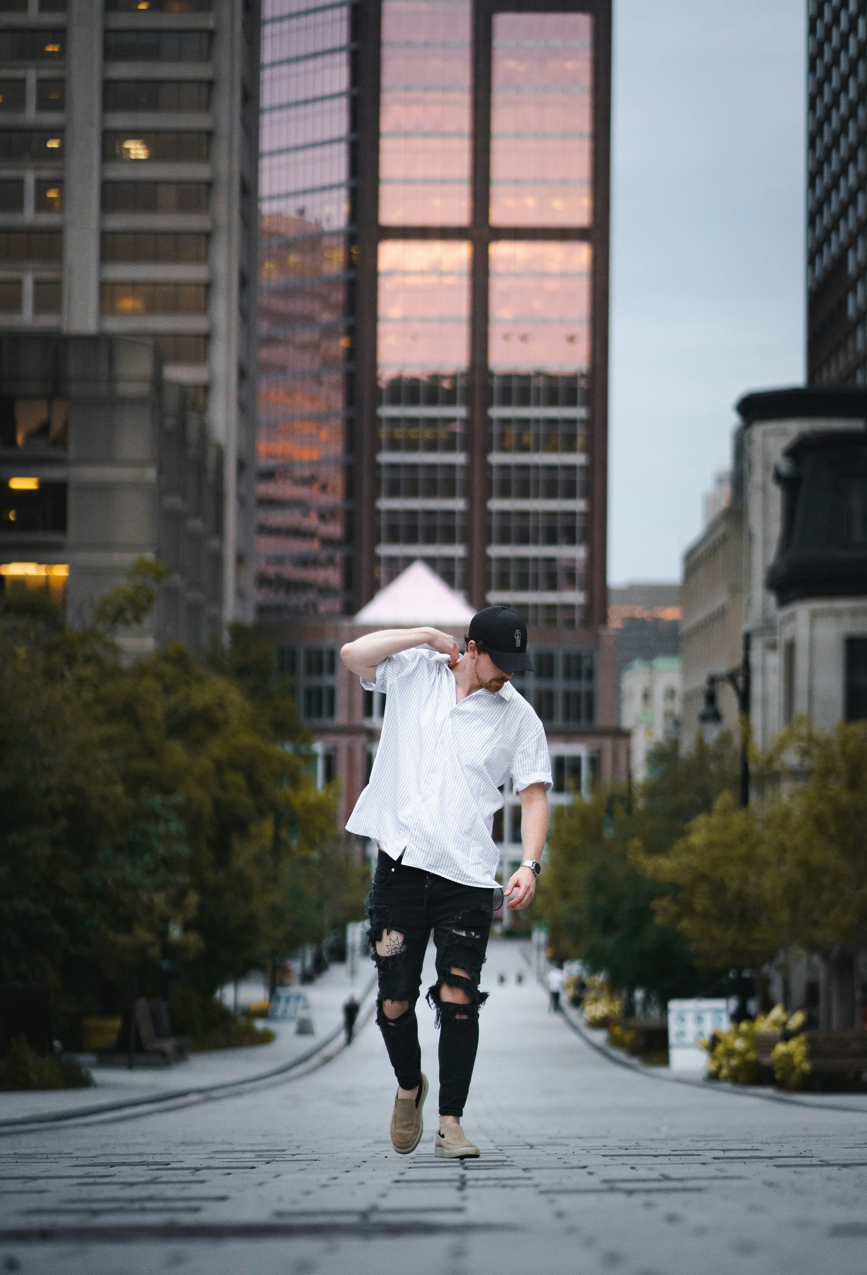 woman in white long sleeve shirt and black pants wearing white hat standing on gray concrete