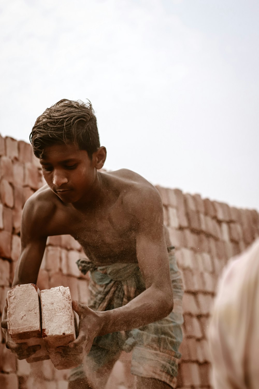 topless man sitting on concrete blocks