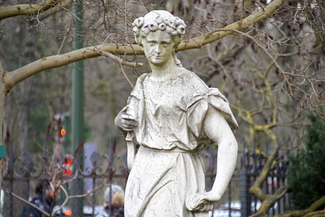 woman holding book statue near trees during daytime