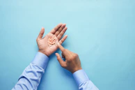 Hands in blue gloves inspecting a row of pills under bright laboratory lights.