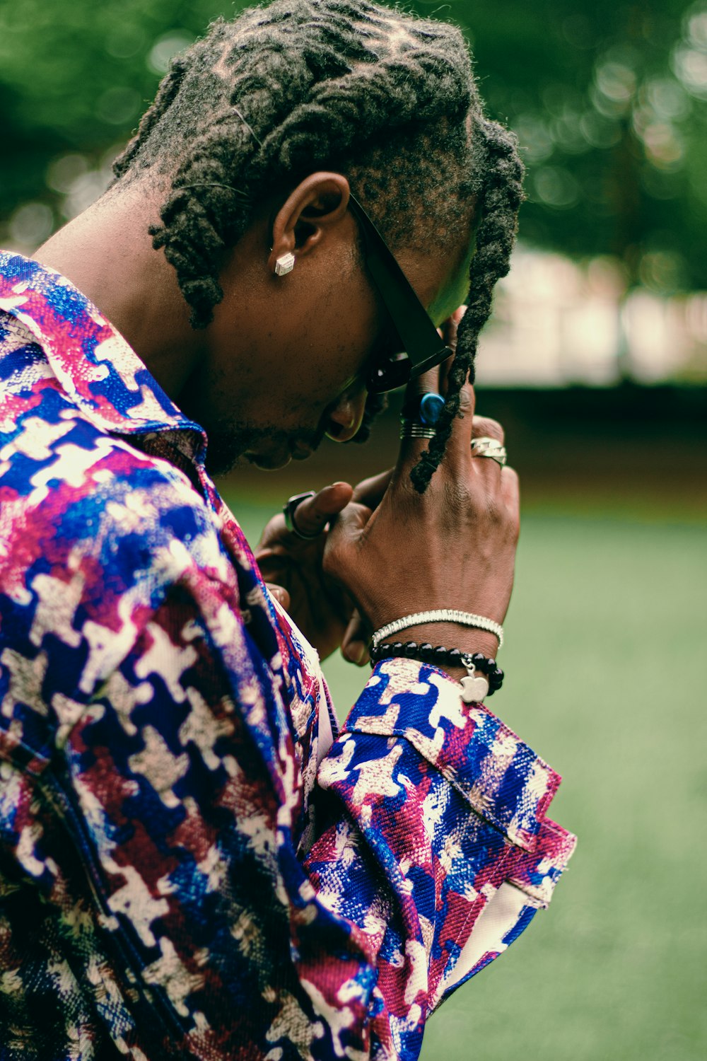 man in blue and red floral shirt wearing black sunglasses