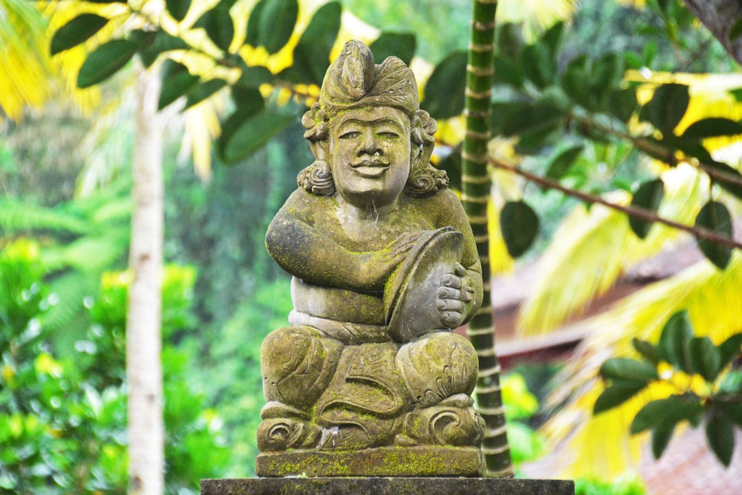 brown concrete statue near green tree during daytime