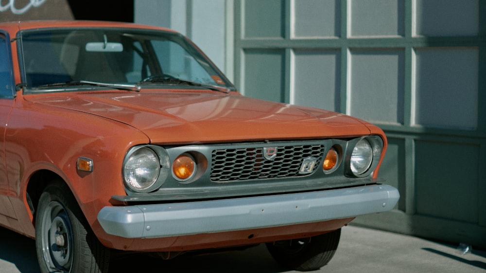 Voiture orange devant un bâtiment blanc