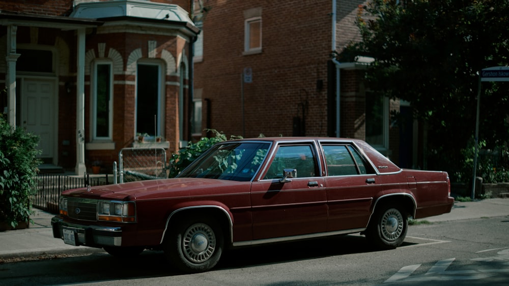 red and white station wagon parked beside brown concrete building during daytime