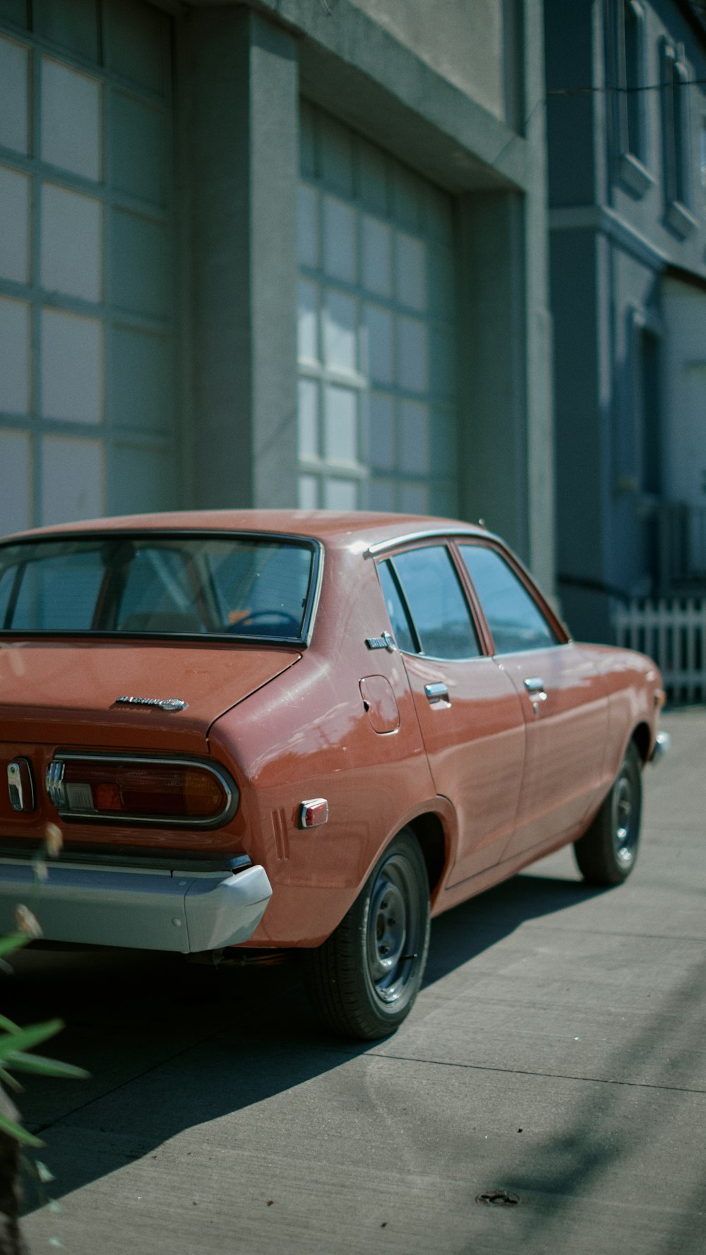 orange sedan parked near white building