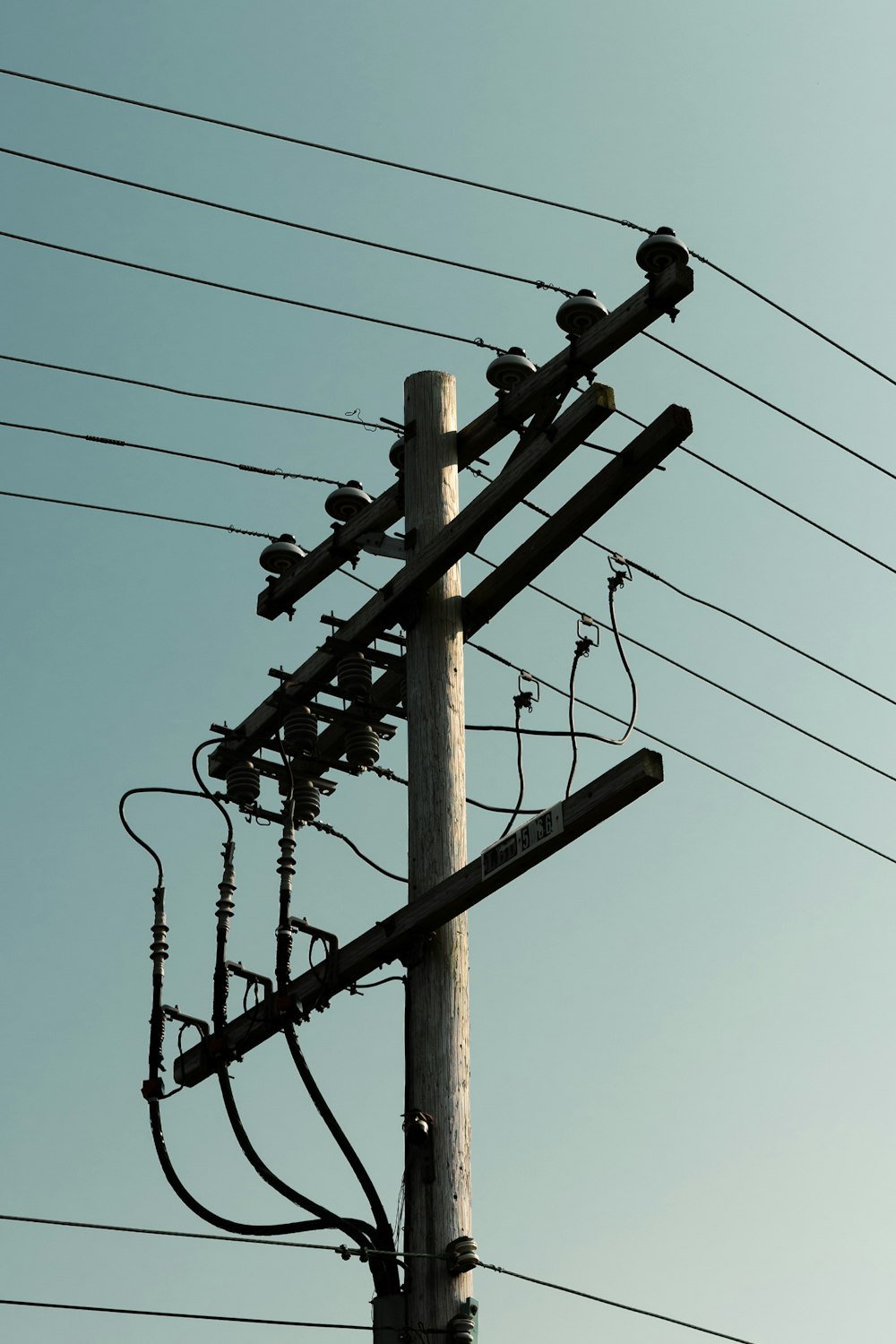 brown wooden electric post under blue sky during daytime