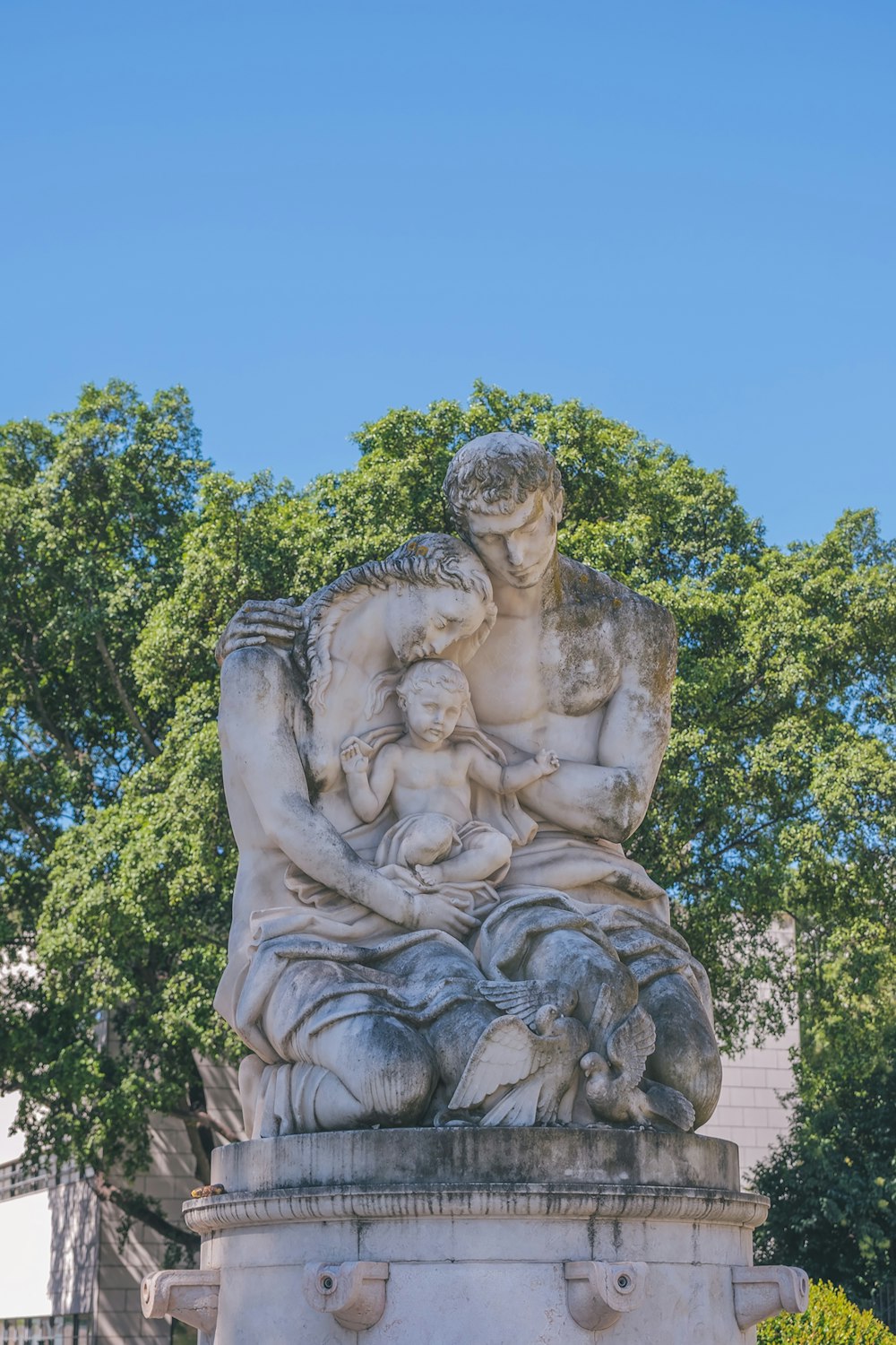 woman in dress statue near green trees during daytime