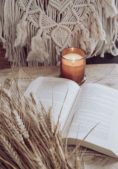 A serene candle burning softly beside an open prayer book on a wooden table.