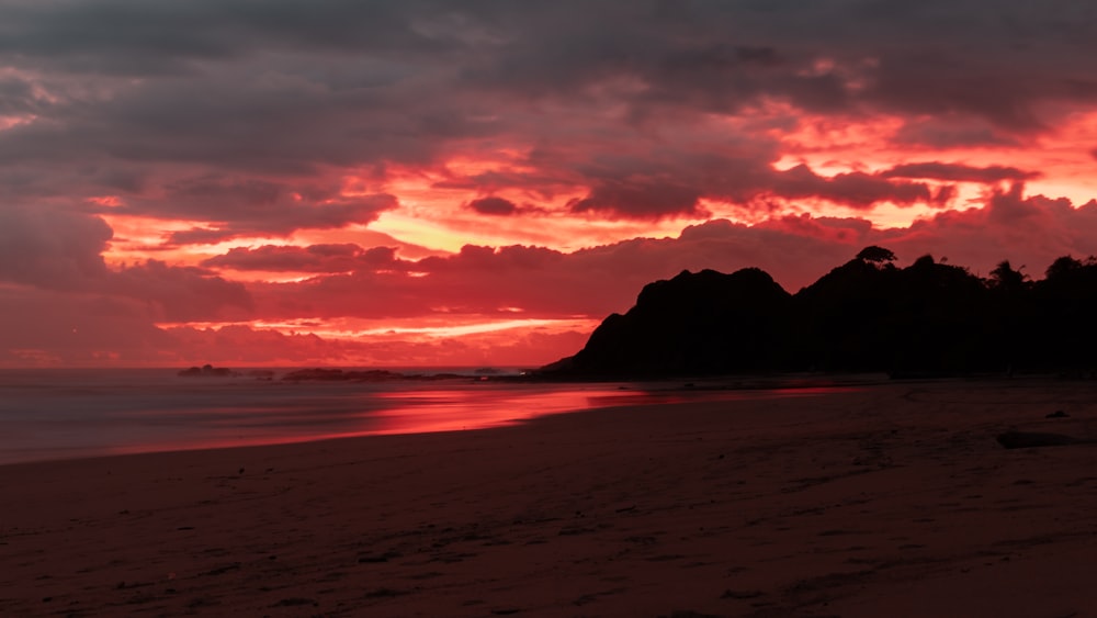 silhouette of mountain near body of water during sunset