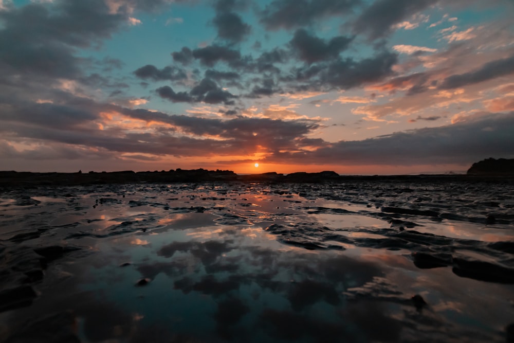 body of water under cloudy sky during sunset