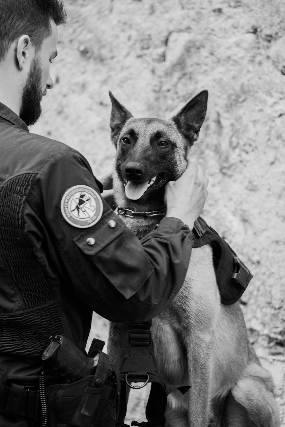 grayscale photo of man in police uniform carrying a dog