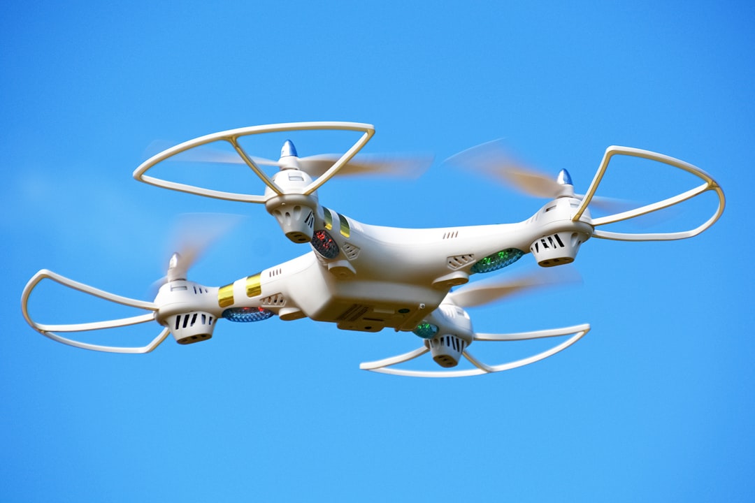 white and yellow drone flying under blue sky during daytime