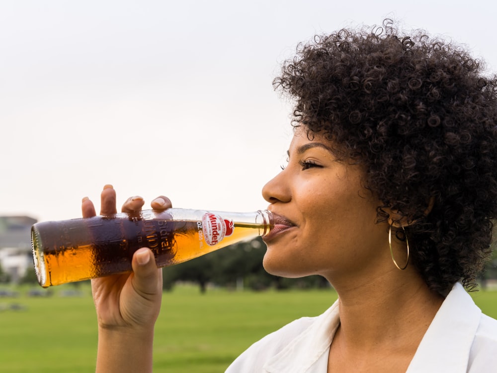 Donna che beve bottiglia di Coca Cola