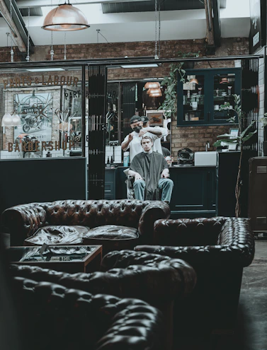 Cozy barbershop interior with dark wood and earthy tones, showcasing a comfortable waiting area.