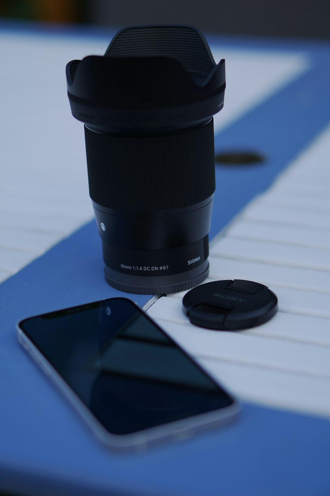 black dslr camera lens beside black samsung smartphone on blue table