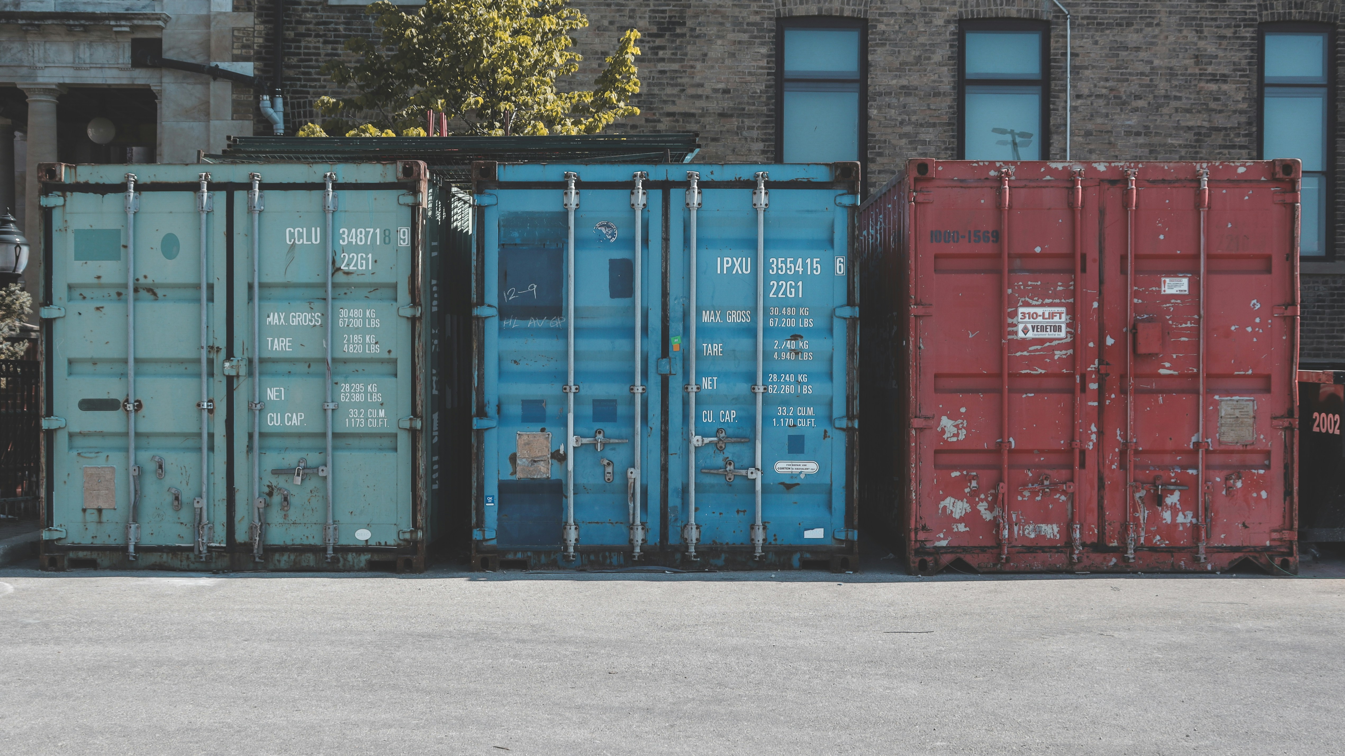 blue steel container van on gray asphalt road during daytime