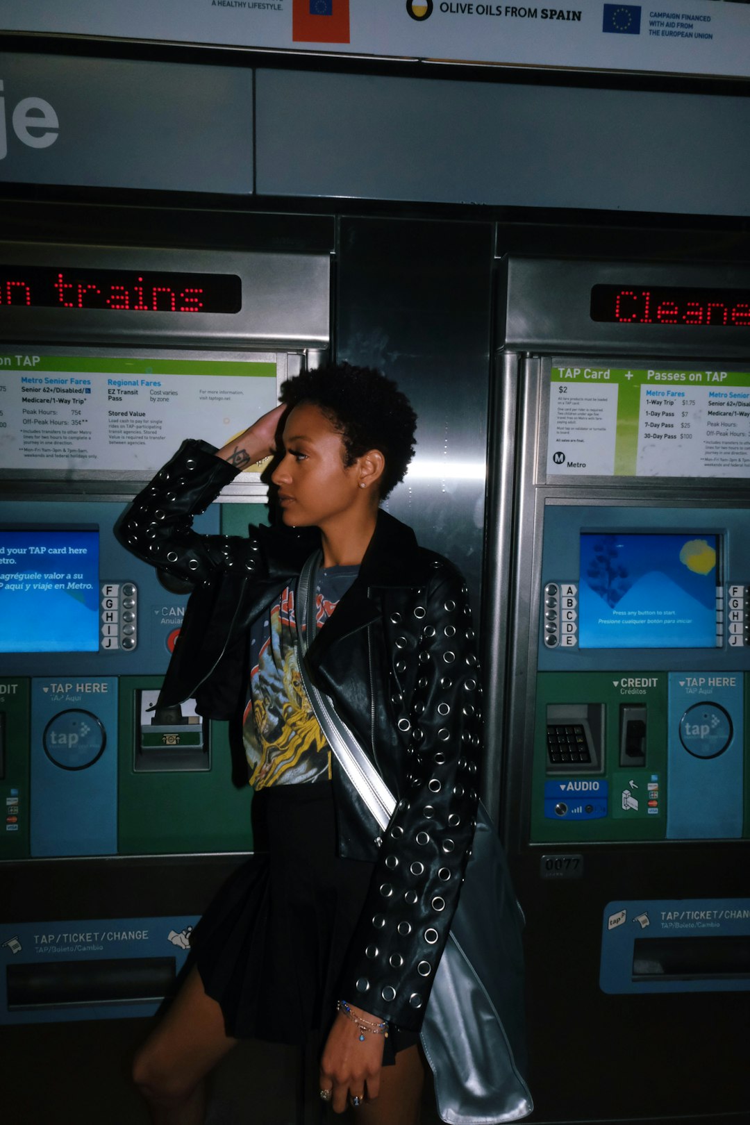 woman in black leather jacket standing near blue and black digital machine