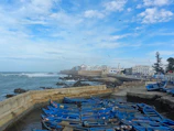 Coastal Essaouira harbor with blue fishing boats and seagulls.