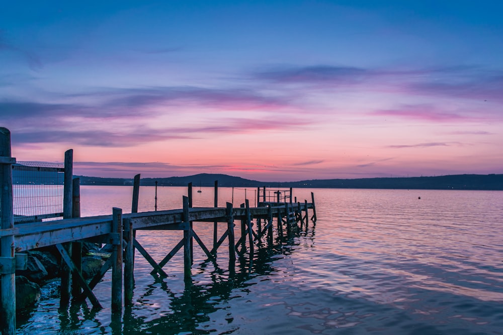 brown wooden dock on sea during sunset