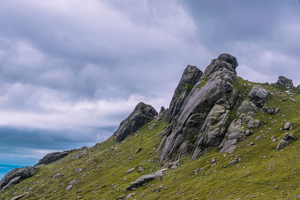 grüner grasbedeckter Berg unter bewölktem Himmel tagsüber