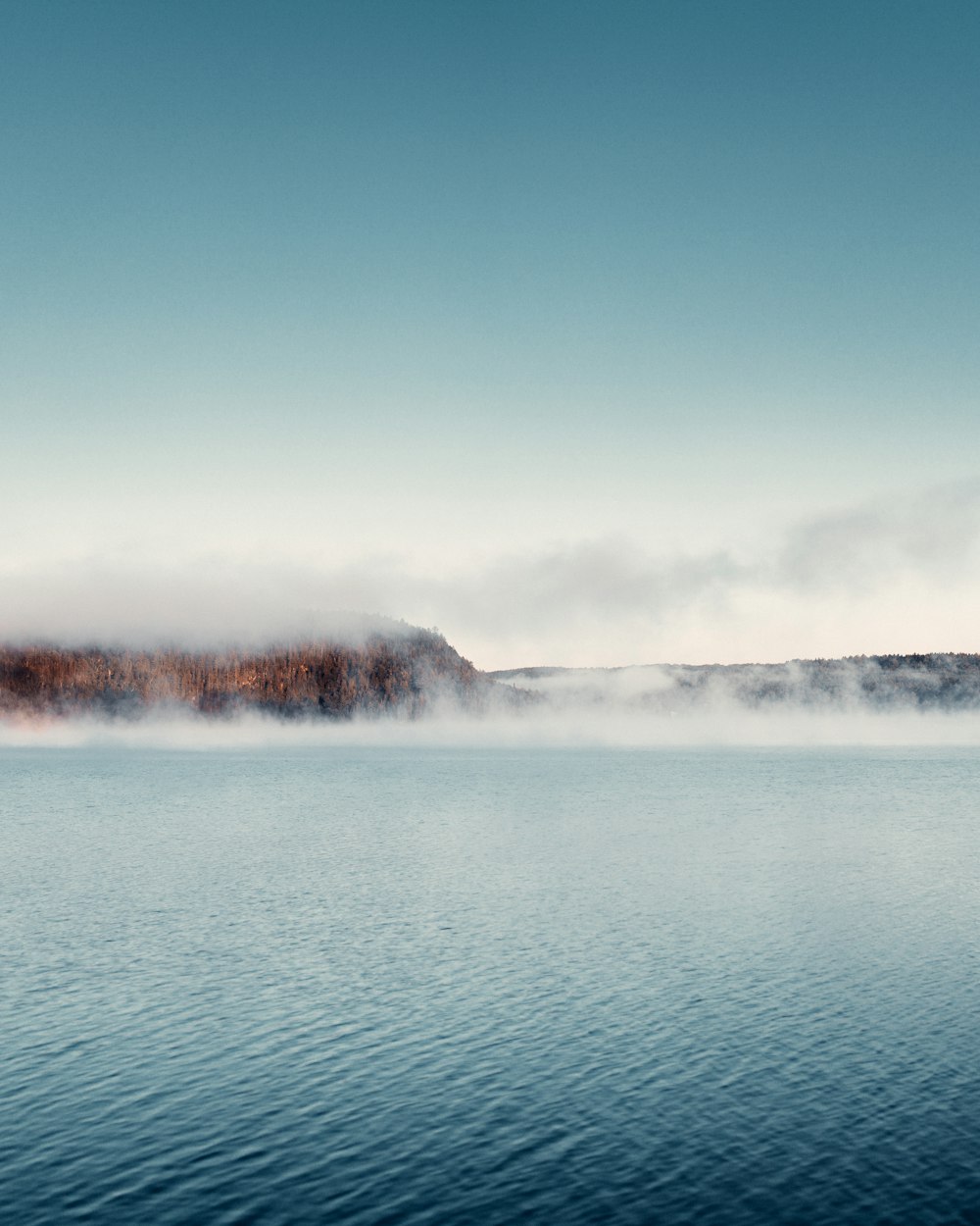 body of water near mountain during daytime