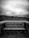 A weathered wooden bench with graffiti reading 'Luv Each Other' is set against a backdrop of overcast skies and grassy dunes. The scene conveys a sense of solitude and contemplation.