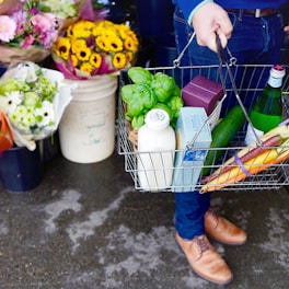 person in blue denim jeans and brown leather boots holding green plastic bag