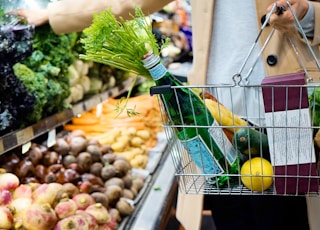 woman in white coat holding green shopping cart