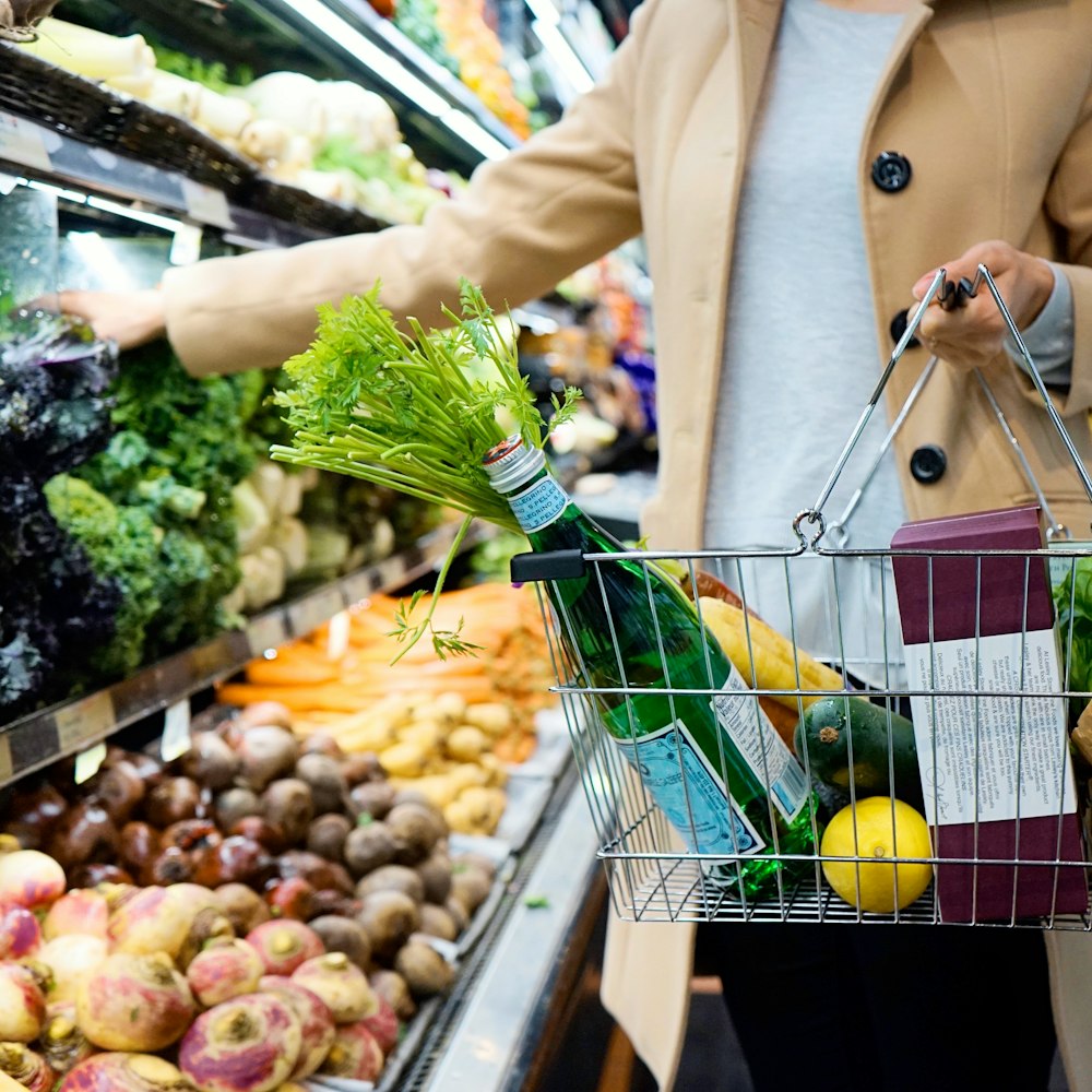 woman in white coat holding green shopping cart