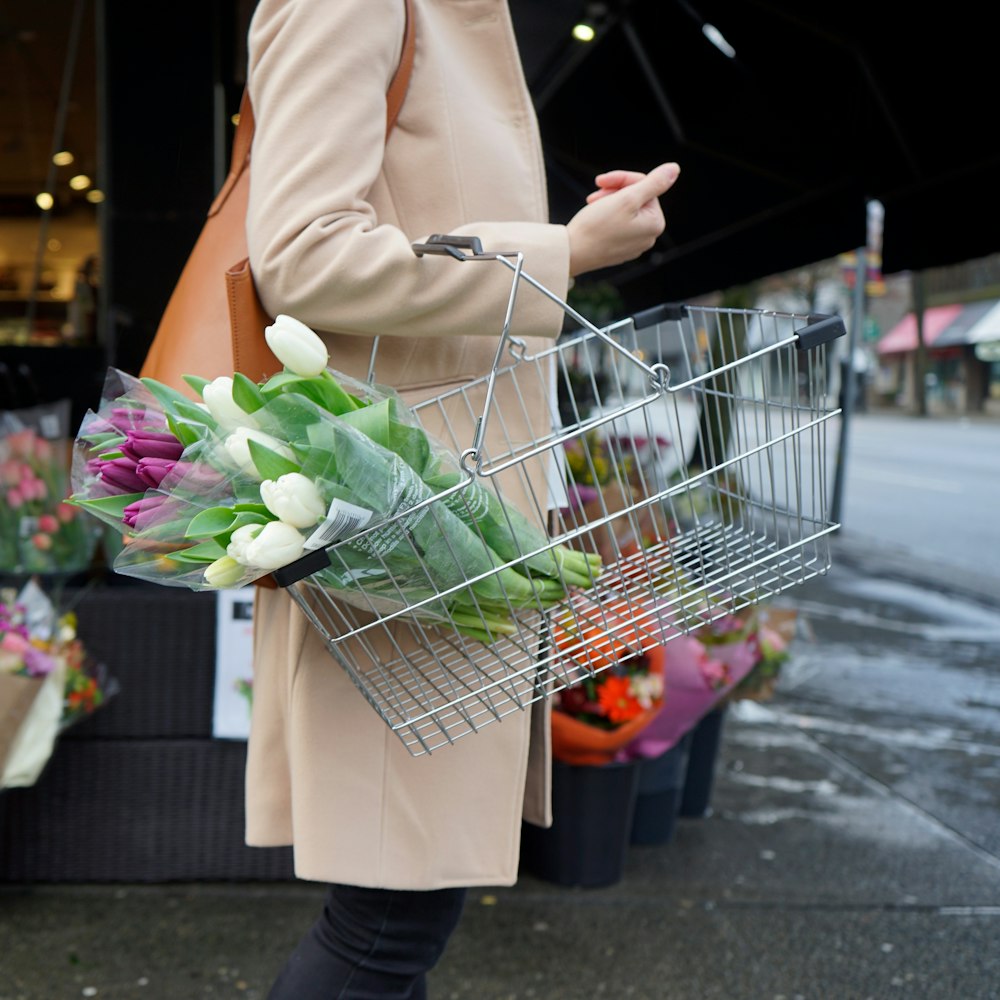 woman in brown coat holding green and pink bouquet of flowers