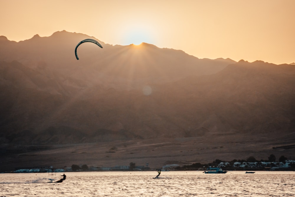 person riding on a parachute over the sea during sunset