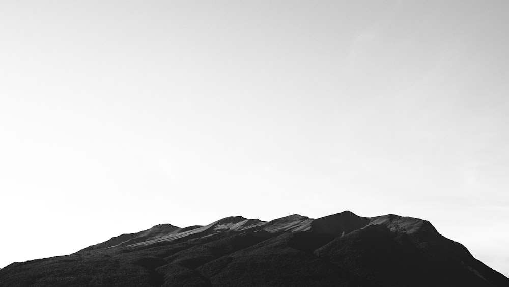 grayscale photo of mountains under cloudy sky