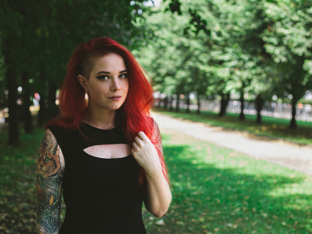 woman in black tank top standing near green grass field during daytime