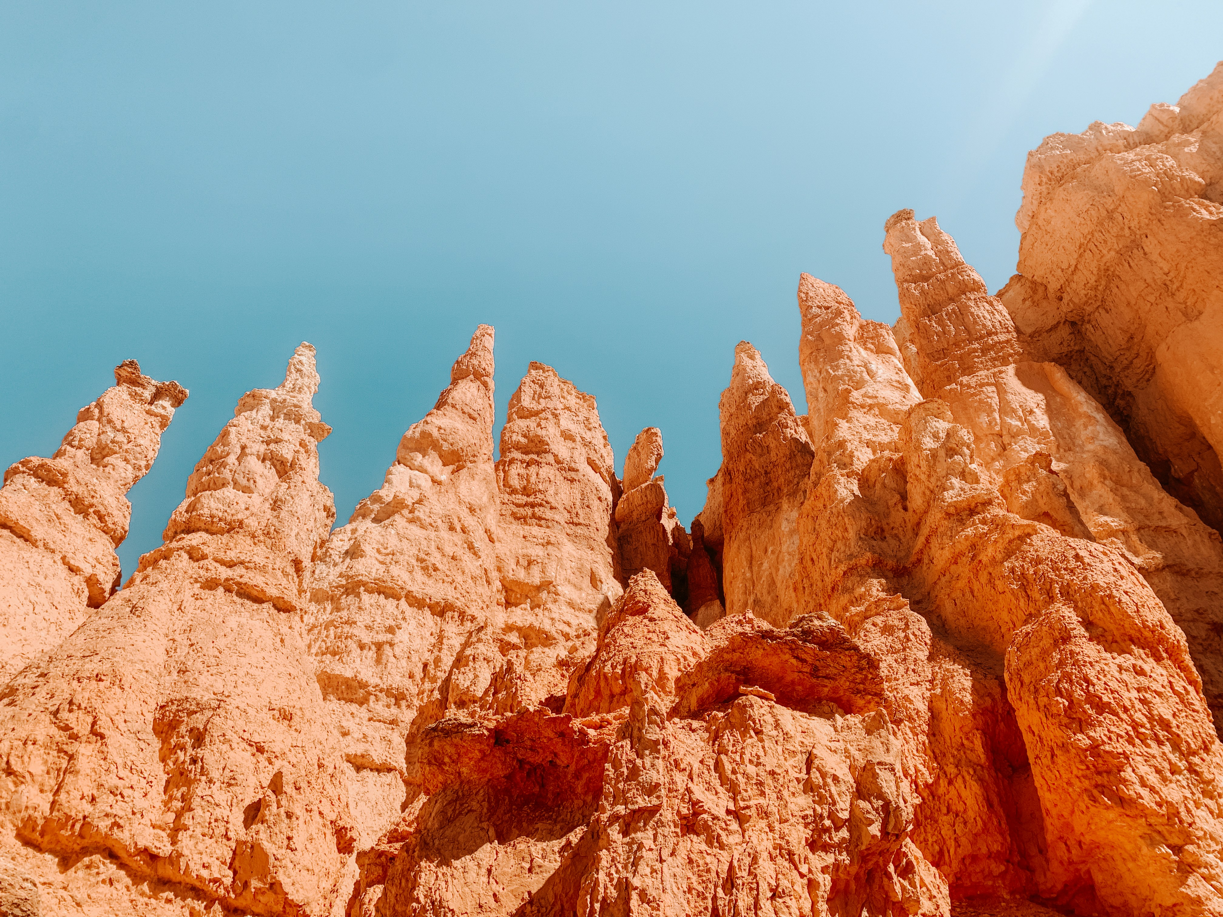 brown rock formation under blue sky during daytime, Bryce Canyon National Park hiking the Hoodoos trail.