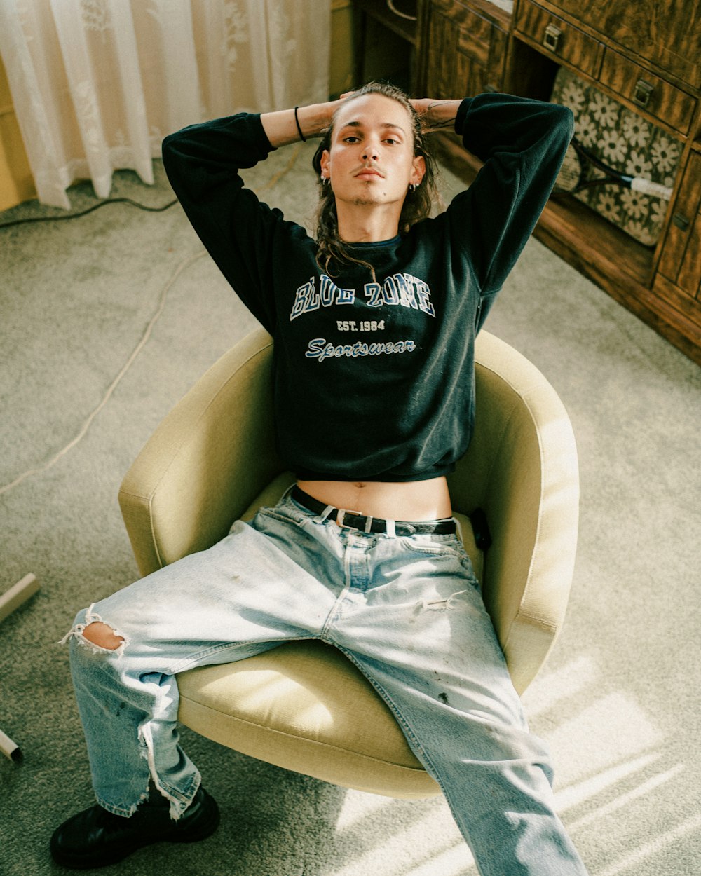 man in black hoodie sitting on brown sofa chair