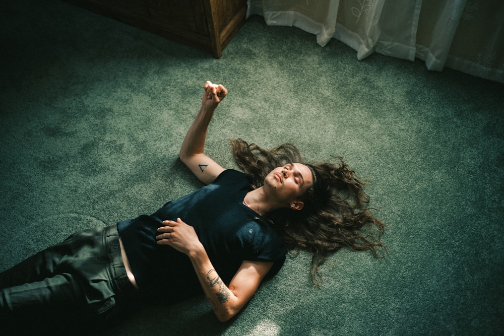 woman in black tank top lying on green carpet