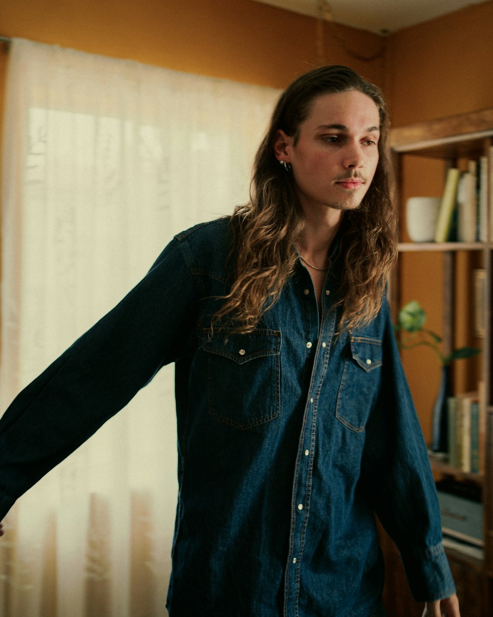 woman in blue denim button up jacket standing near white curtain