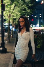Close-up of Bigg Britt in street-luxe outfit with city skyline glowing behind her at night.
