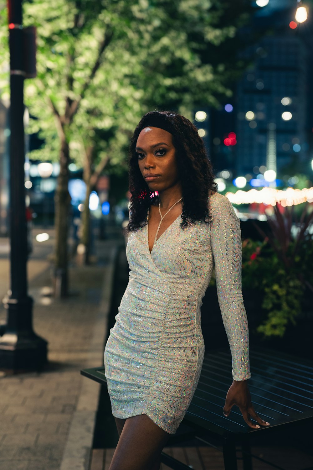 woman in white long sleeve shirt and gray skirt sitting on bench during night time