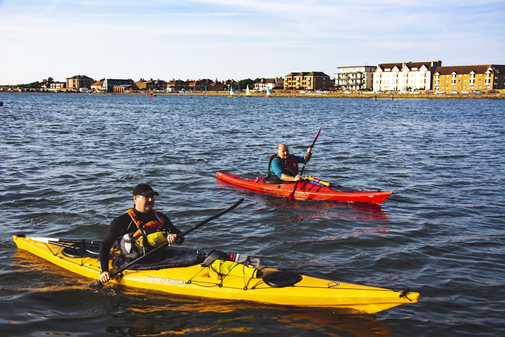 man and woman riding on yellow kayak on sea during daytime
