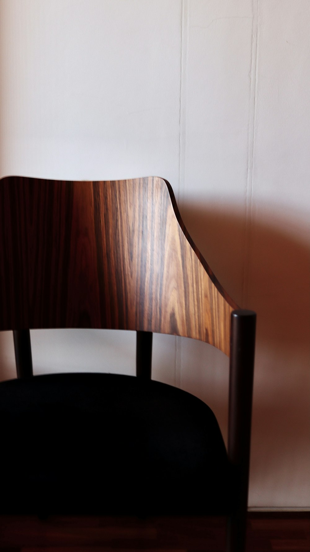 chaise en bois marron à côté d’un mur blanc