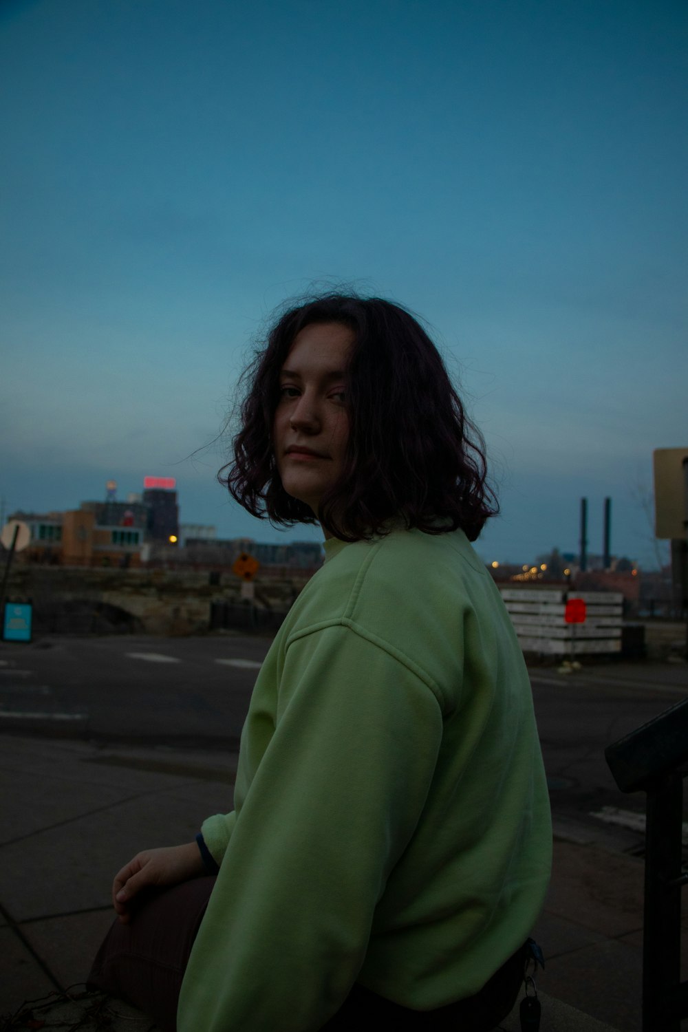 woman in green long sleeve shirt standing on sidewalk during daytime