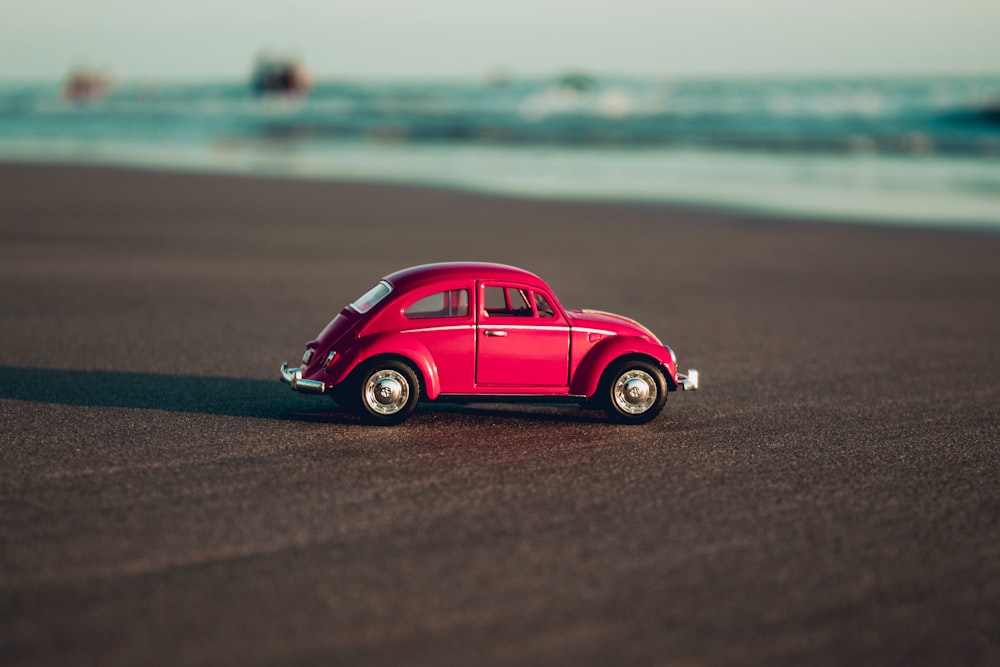 red volkswagen beetle on beach shore during daytime