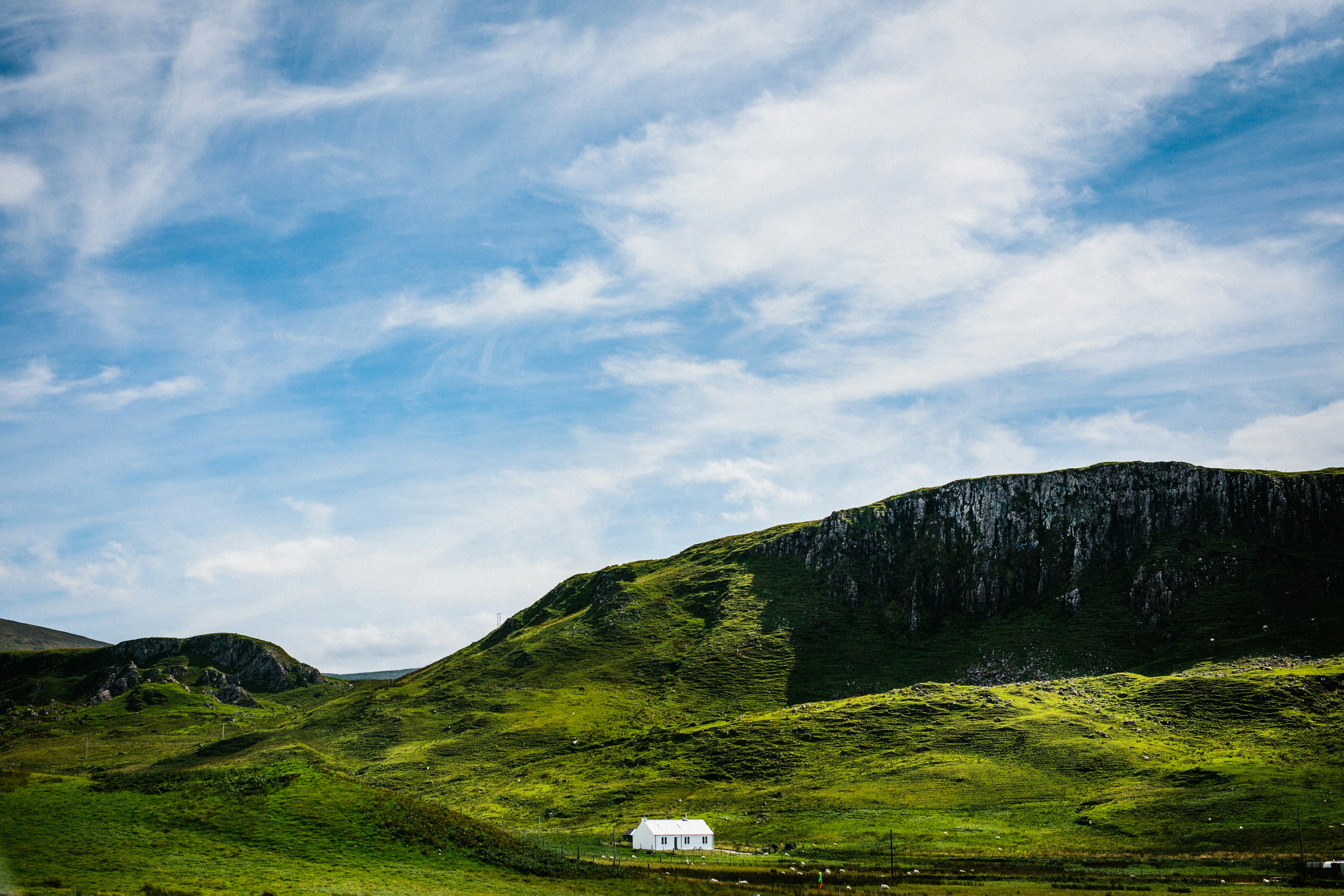 Green grass field and mountain under blue sky