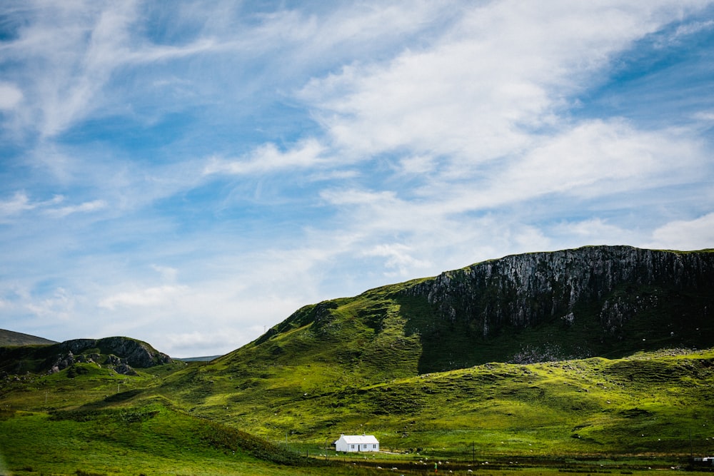 green grass field and mountain under blue sky during daytime